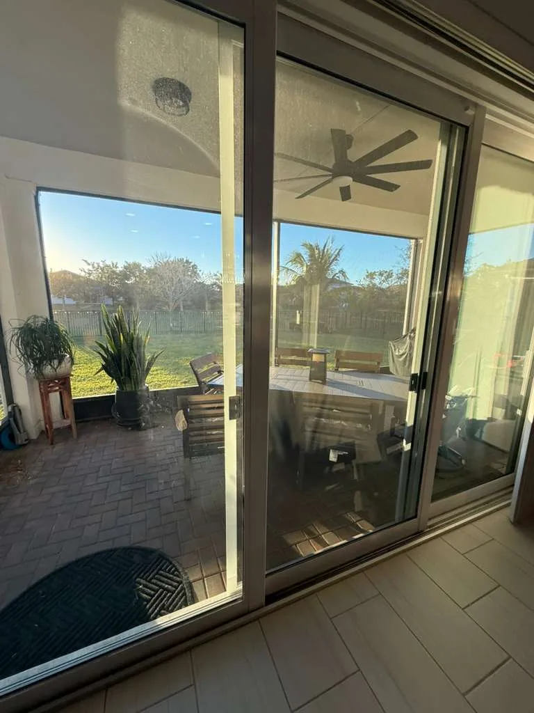 A technician replacing the rollers on an impact sliding glass door